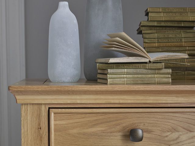 经典卧室的抽屉柜由橡木家具与花瓶和一堆旧书在灰色墙壁前面