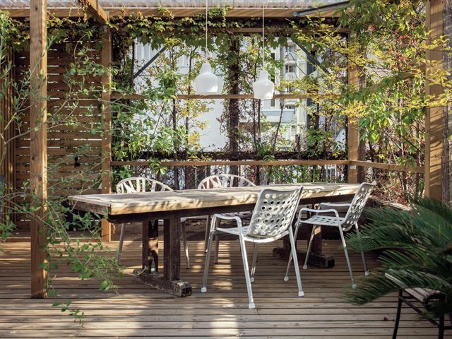 在室外餐厅的露台或阳台上放置一张木制桌子和几把白色椅子
