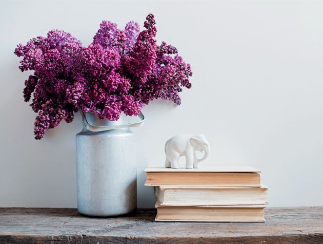 紫色的花插在银花瓶和书的壁炉架上