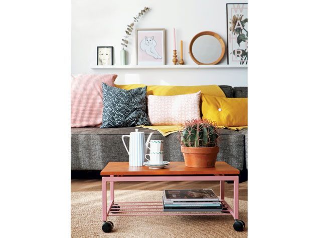 白色方案的客厅配有灰色沙发、粉色和黄色坐垫，咖啡桌上有仙人掌