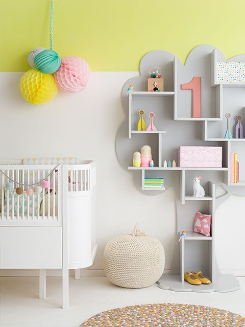 Scandi风格的育婴房，黄色和白色的墙壁，现代的婴儿床和树状的灰色架子
