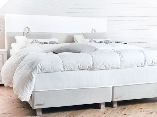 灰色的床架上放着白色的床垫，上面还铺着白色的羽绒被