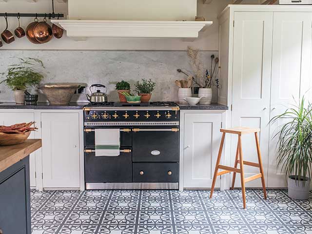 传统的黑色烤箱配有黑白瓷砖地板和质朴的炖锅，goodhomesmagazine.com