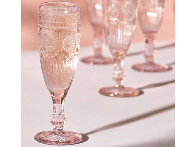 下一个浮雕香槟酒长笛在桌子上与粉红色的背景