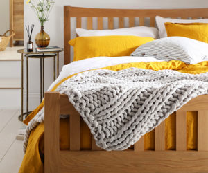床与黄色床单和灰色扔- pantone颜色的2021年- goodhomesmagazine.com