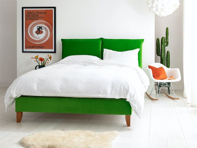 明亮的绿色双人床在白色的卧室方案——goodhomesmagazine.com