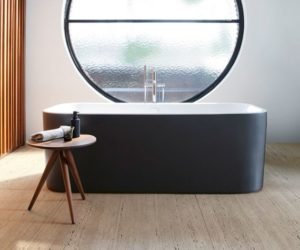 圆形窗户前独立的黑色浴缸