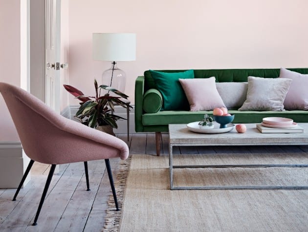 有粉红色的墙壁，绿色沙发，咖啡桌和粉红色椅子的客房