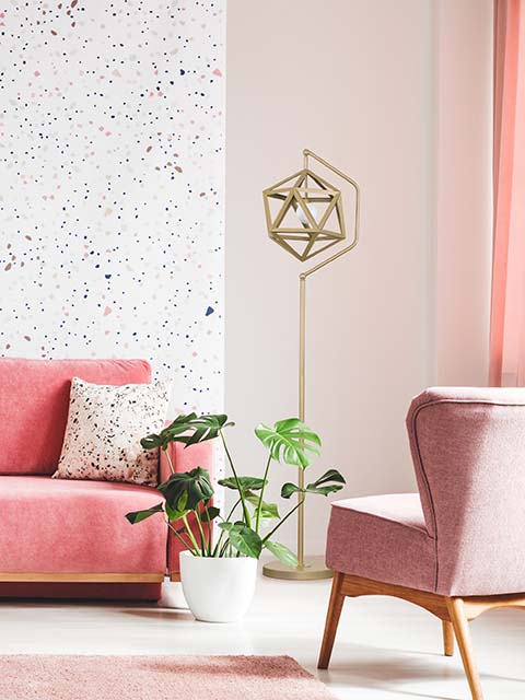 舒适的客厅角落与粉红色沙发覆盖着在装饰的墙壁背景特征和人工植物的粉红色的沙发覆盖着左侧/舒适的室内概念/装饰想法的粉红色枕头