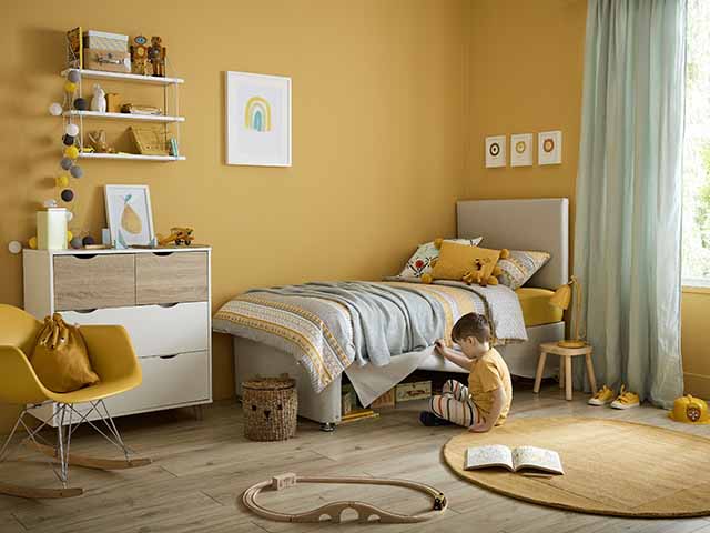 安静的夜晚明亮的黄色卧室与孩子;床，书架和地毯，goodhomesmagazine.com