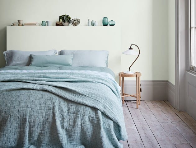 现代风格的卧室，灰绿色的墙壁，蓝绿色的床上用品和木地板