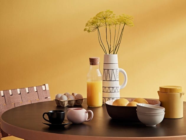餐厅的墙漆是暗黄色的，有一张圆形的木桌，上面放着早餐用品
