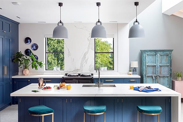 厨房岛有三个蓝色的椅子，吊灯和早餐