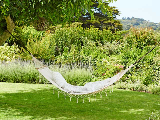 白色吊床附着在一棵草地上的树木 -  2021庭院家具 -  Goodhomesmagazine.com