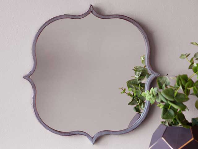 挂在墙上的一面有弯曲边和尖边的镜子。花园镜子