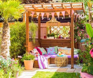 一个长满草的花园，用彩旗、靠垫和毯子装饰了凉棚——花园派对的必需品——Goodhomesmagazine.com