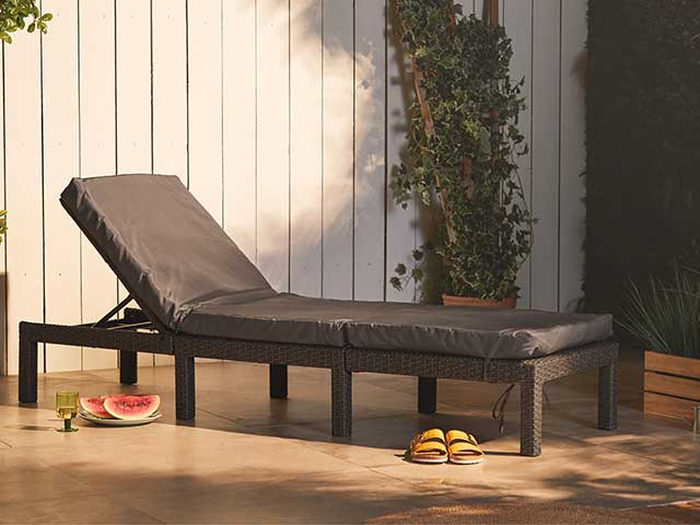 黑色藤阳光躺椅上有一对凉鞋在前面 -  2021花园家具 -  Goodhomesmagazine.com