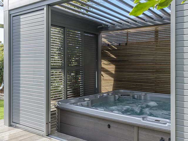 光滑的装有百叶窗板的树冠由粉饰铝,里面一个热水浴缸