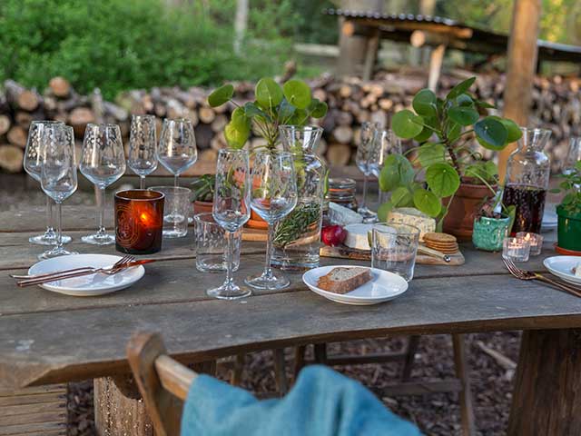 酒杯和食品在室外设置不良木桌子上,goodhomesmagazine.com