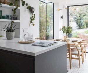 这个墨尔本风格的住宅采用开放式厨房，深色的单元、白色的工作台和背景有落地窗的餐桌