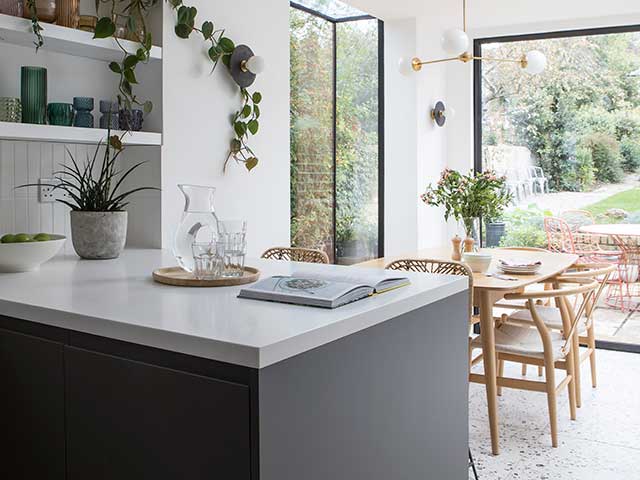 这个墨尔本风格的开放式厨房有深色的单元，白色的工作台和餐桌，背景有落地窗户